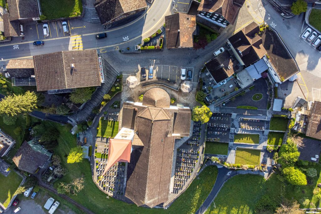 Die Drohnenfotografie zeigt den Dorfkern von Bürglen im Kanton Uri mit Blick auf die Kirche.