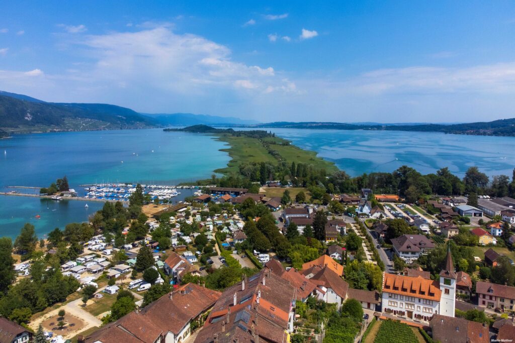 Die Drohnenfotografie erfasst das malerische Städtchen Erlach im Kanton Bern. Das Bild zeigt die historische Altstadt von Erlach, die sich entlang des Ufers des Bielersees erstreckt. Die charakteristischen Häuser mit ihren roten Dächern und den malerischen Fassaden fügen sich harmonisch in die Umgebung ein.