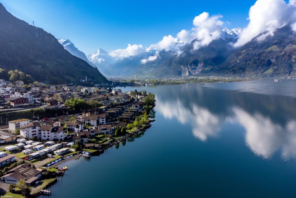 Die Drohnenfotografie erfasst den Urnersee und das Dorf Flüelen im Kanton Uri. Im Hintergrund befindet sich der mit schneebedeckte Bristen.