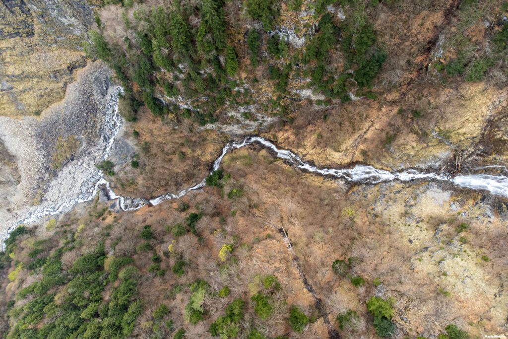 Ein klarer Bach fliesst durch das idyllische Gitschital im Kanton Uri. Das Gewässer schlängelt sich sanft durch die karge Landschaft.