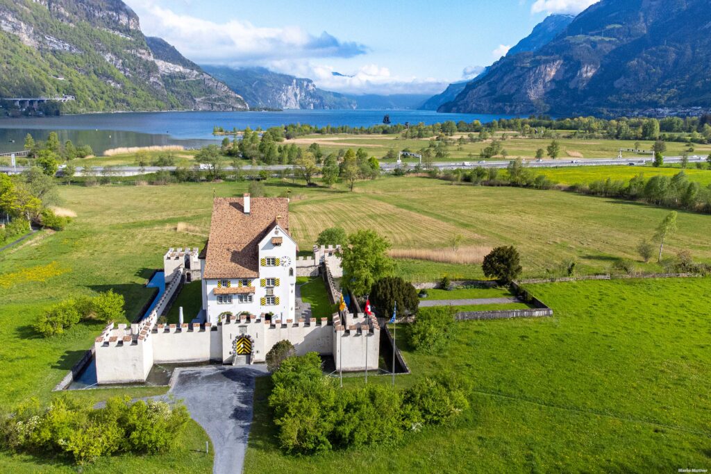 Die Drohnenfotografie zeigt das Schloss A-Pro mit dem Urnersee im Hintergrund.