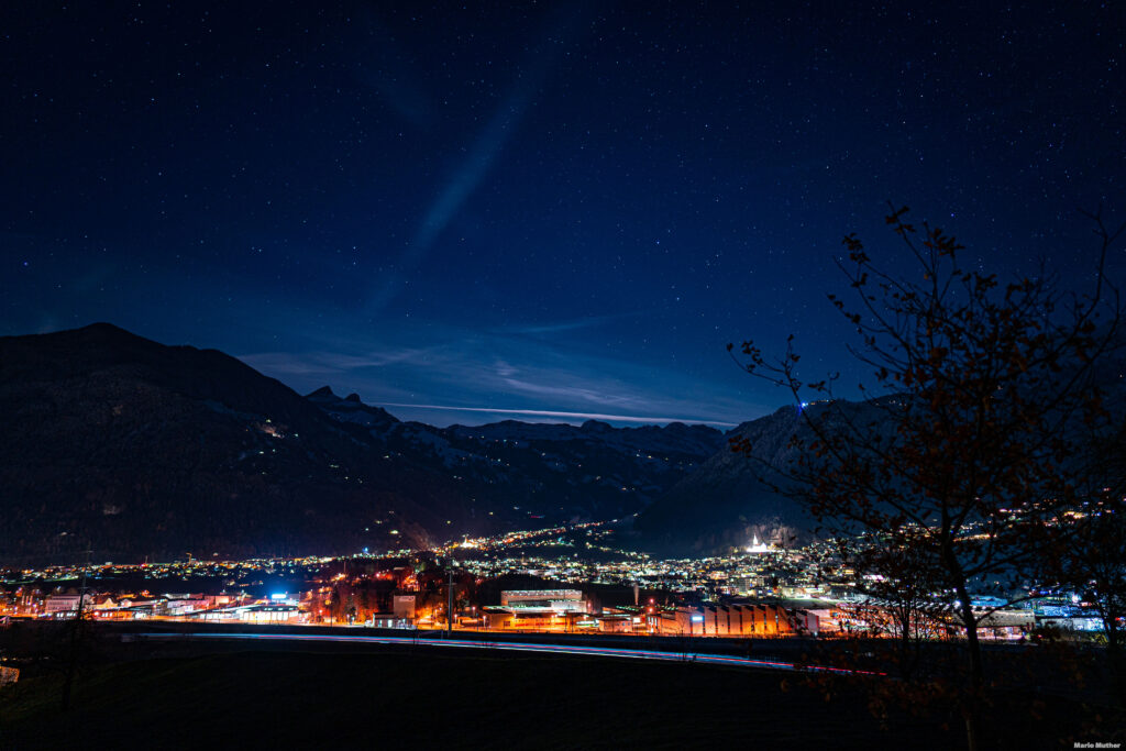 Die Drohnenfotografie zeigt den Urner Talboden in der Nacht, mit Blick auf das Haldi und Waldi im Kanton Uri. Die Lichter der Dörfer schaffen ein beeindruckendes Spiel von Licht und Schatten, während der Himmel mit Sternen gesprenkelt ist und eine romantische Atmosphäre erzeugt.